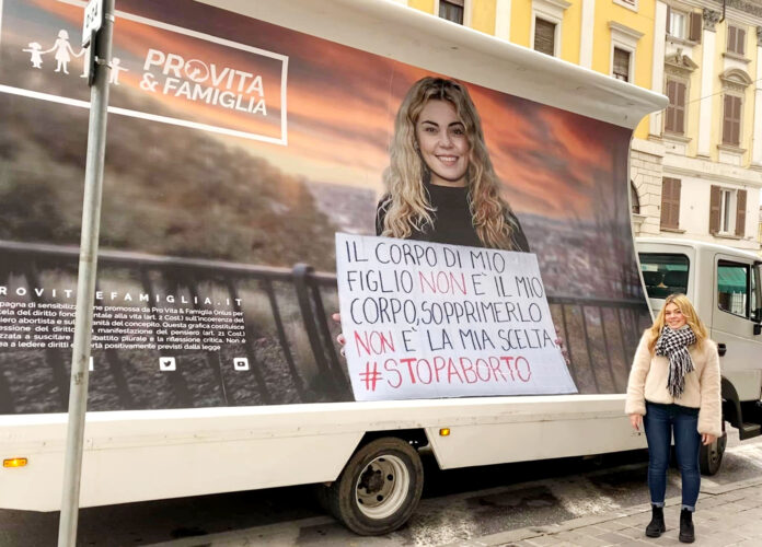 Anna Bonetti accanto al manifesto censurato dal sindaco di Reggio Calabria Falcomatà